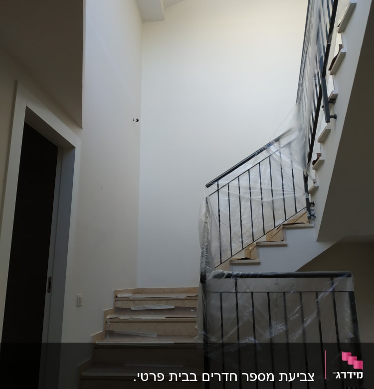 מדרגות עם מעקה מכוסה בניילון להגנה מצבע